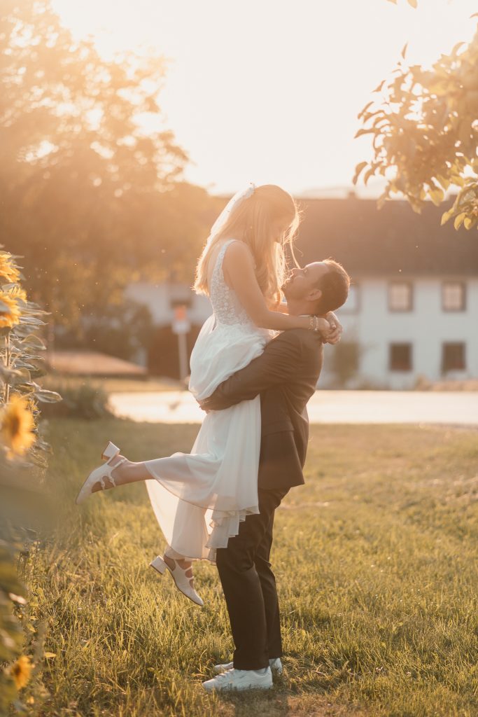 Bräutigam hebt die Braut beim romantischen Hochzeitsshooting im Abendlicht beim Kulturstadl Reckeneder in Treffling hoch